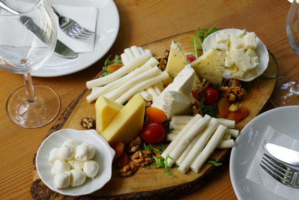 A delicious assortment of cheeses, nuts, and fruits artistically arranged on a wooden platter.